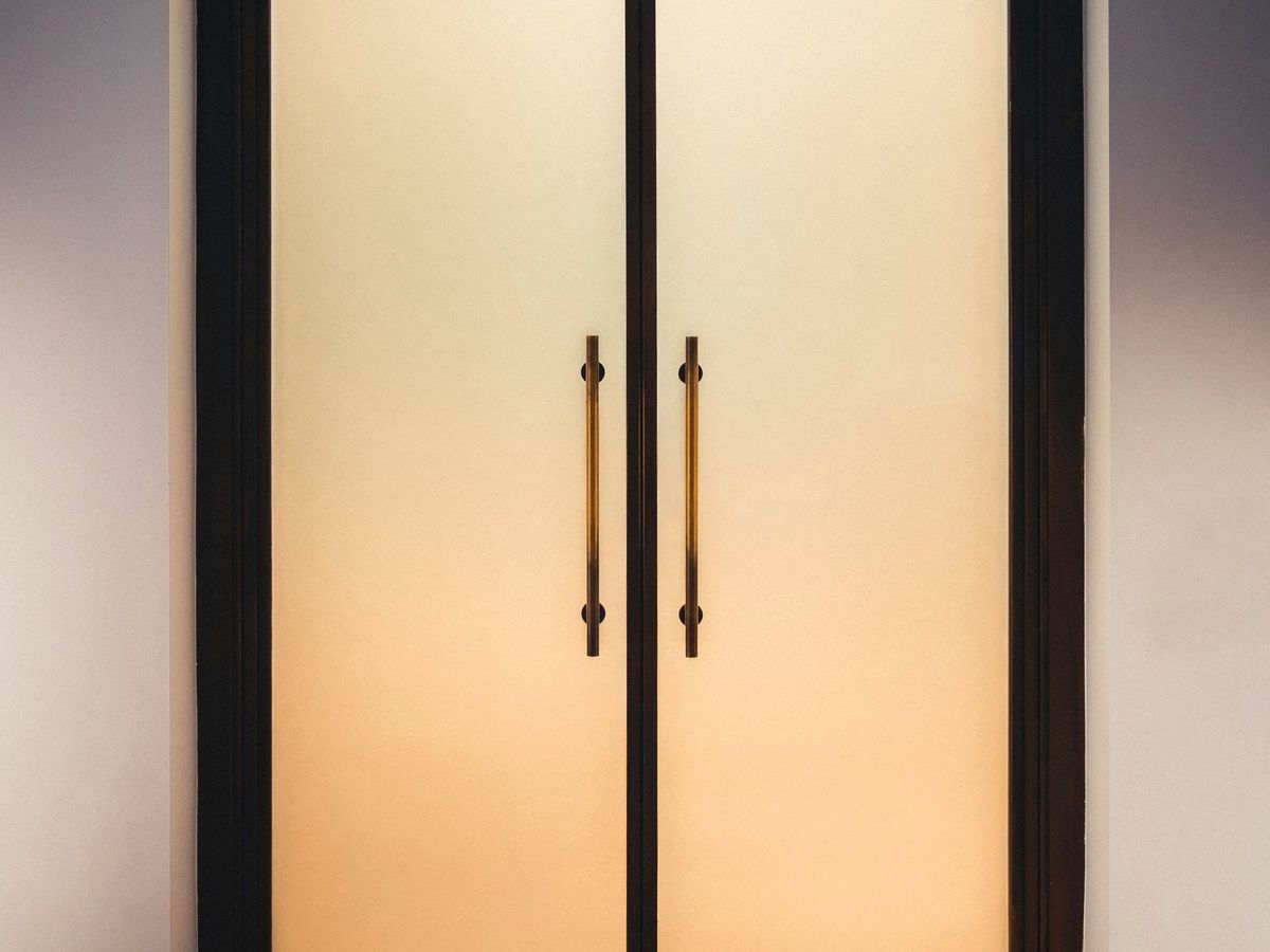 Frosted etched-look glass office doors glowing with warm interior light, a decorative covering finish
