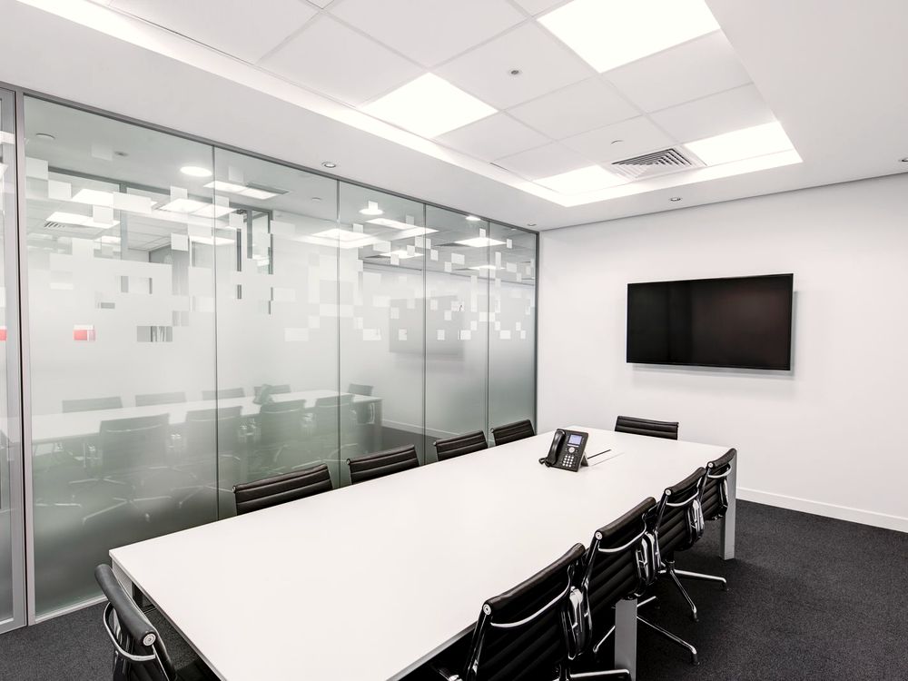 Modern office conference room enclosed in glass walls with a frosted privacy band