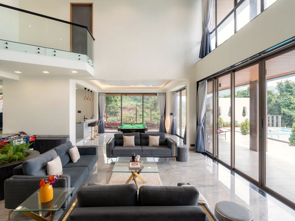 Luxury residential living room with full-height glass walls opening to a private pool and garden