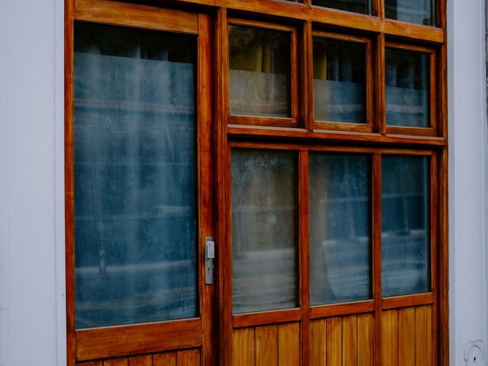 Wood-framed retail storefront with large glass display panels reflecting the street