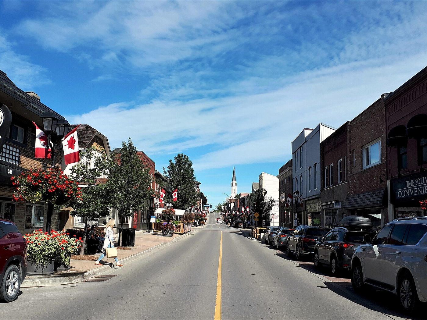 Lower Main Street in Newmarket's heritage district with Canadian flags, hanging flower baskets and storefronts