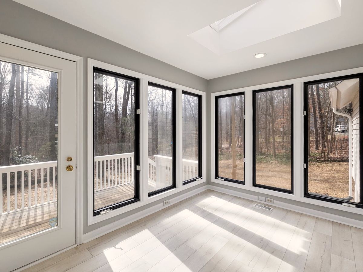 Sunroom with large windows treated with solar control covering, the forest view crisp and the room bright with no visible darkening
